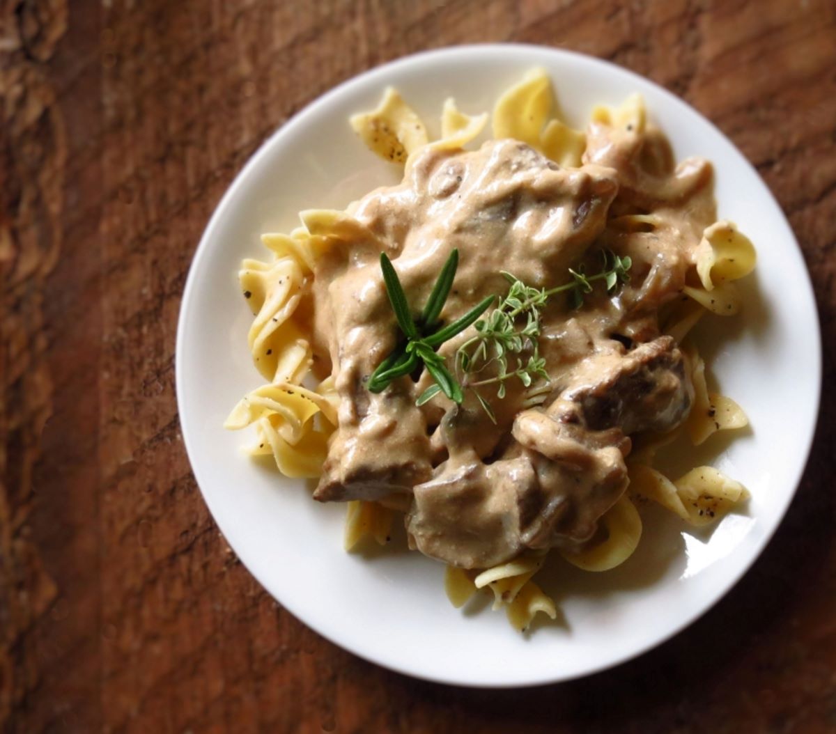 Beef stroganoff over a plate of noodles.