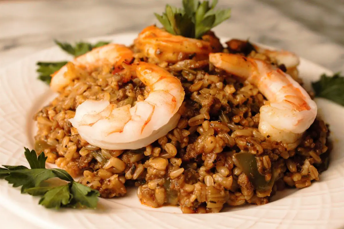 Jambalaya in a white dish topped with beautifully cooked shrimp and garnished with parsley
