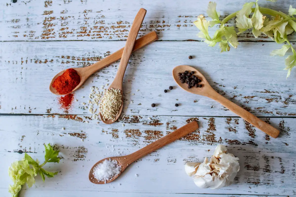 Spices in wooden spoons arranged in a decorative manner over a wooden surface.